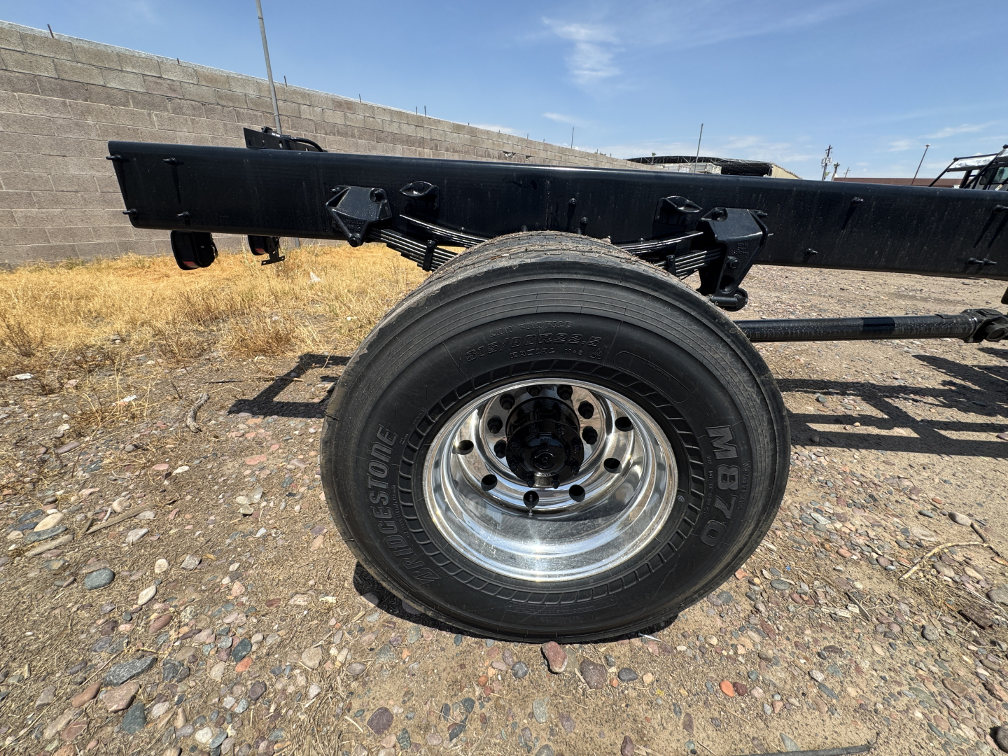 Wheel and chassis frame of a 2027 Mack GR44B cab and chassis showing single rear wheel with Bridgestone tire and metal hub, side view