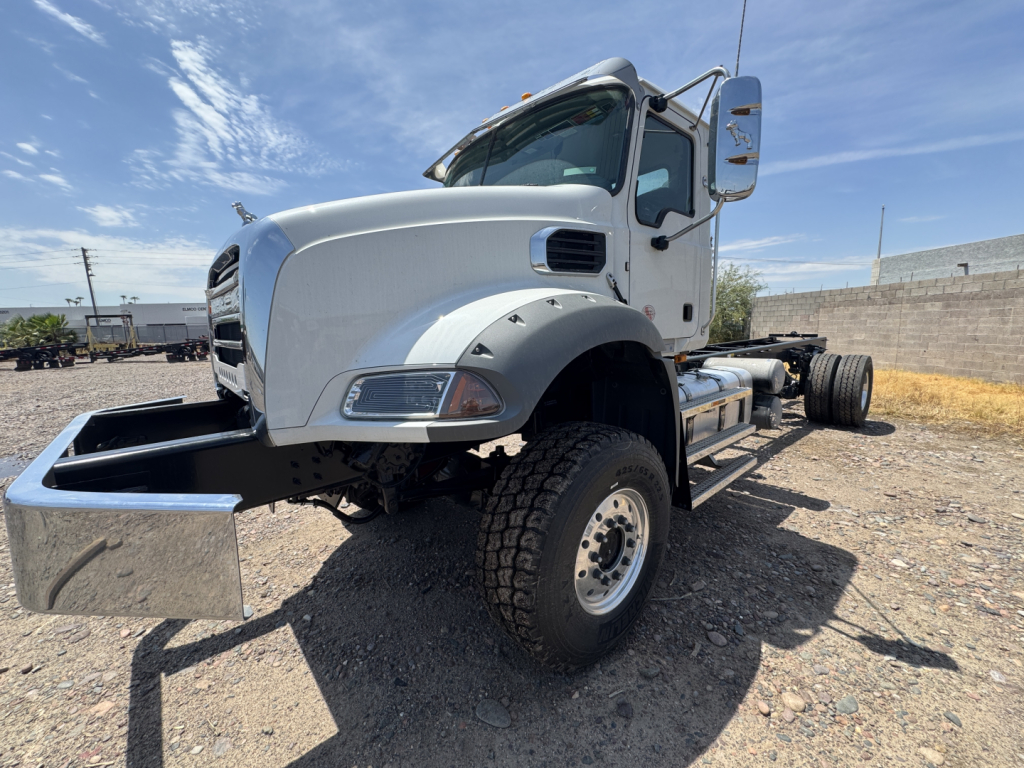 Truck cab chassis showing front fender, hood, wheel, and side mirror with chrome fuel tank behind cab, white paint.