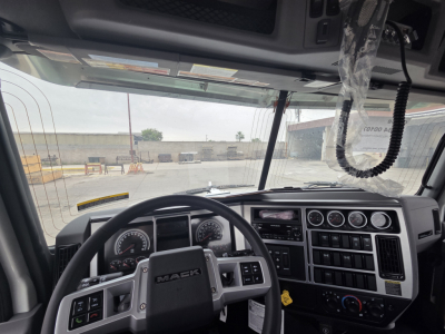 Cab interior of a Mack truck showing steering wheel, dashboard gauges, and control panel.