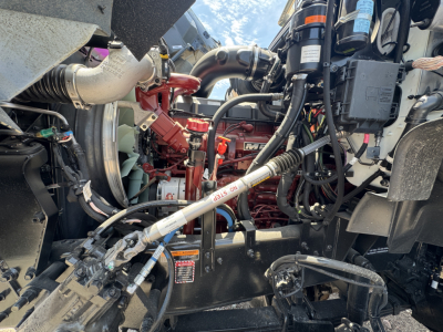 Truck engine bay showing 2027 Mack GR44B cab and chassis with visible red engine, hoses, wiring, and hydraulic lines.