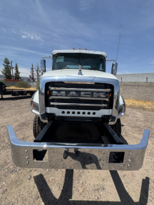 Front view of a white 2027 Mack GR44B cab and chassis truck with chrome bumper and grille, large heavy-duty bumper with openings, Mack logo on grille.