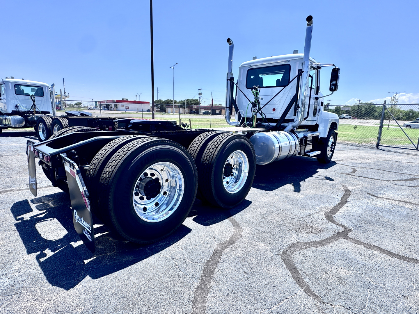 Tractor-trailer chassis of a 2027 Mack PI64T daycab truck showing rear tandem axles and chrome fuel tanks.