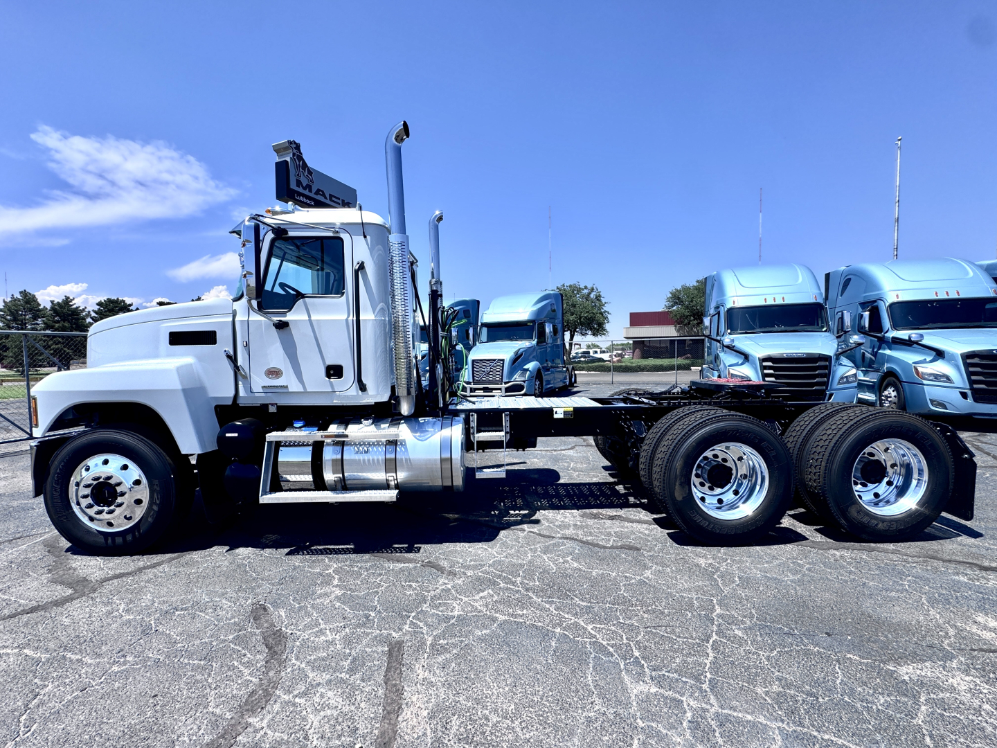 Mack PI64T conventional daycab truck chassis in white showing fuel tanks and rear axles with dual rear wheels.