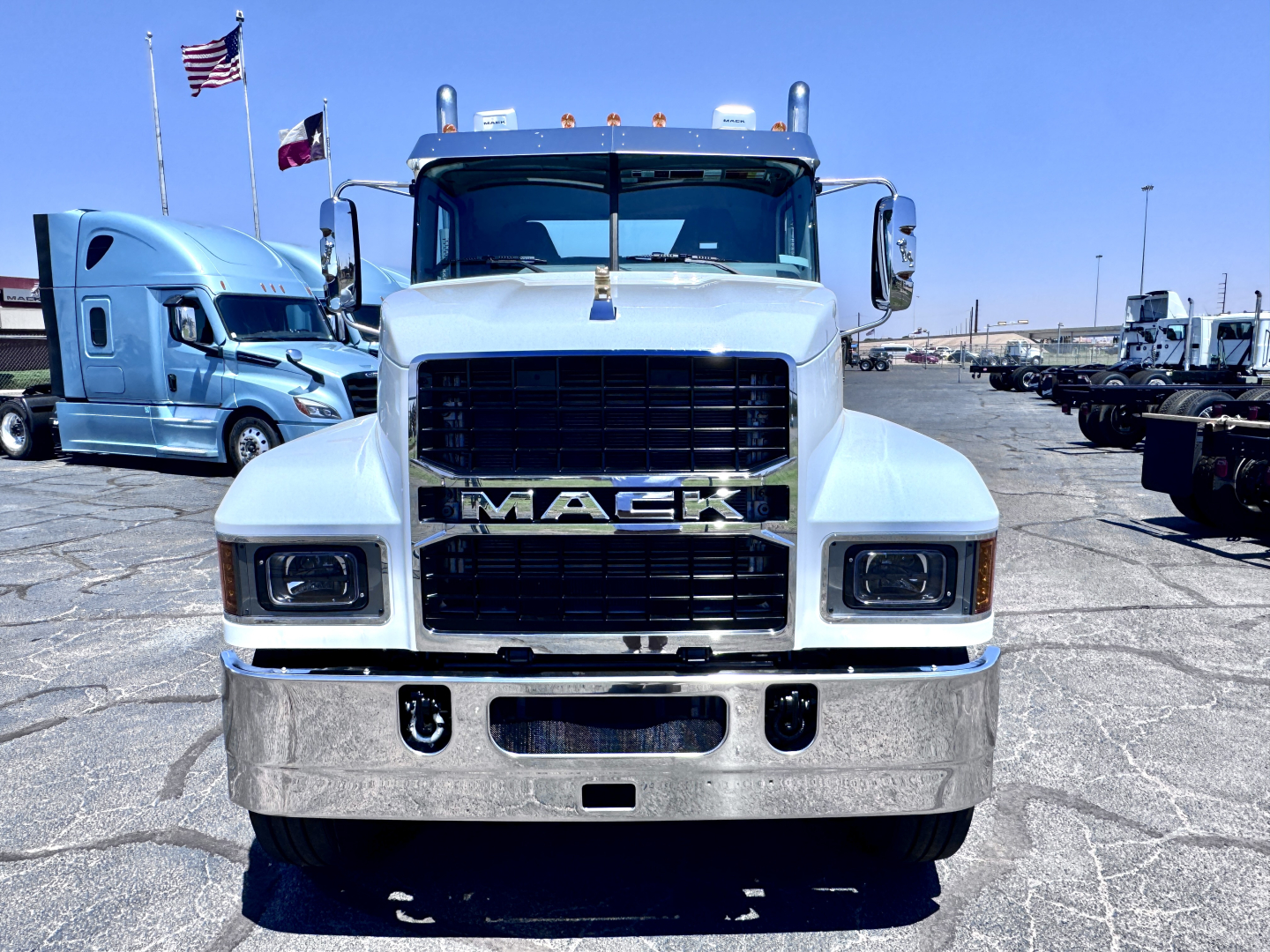 Front view of a new white Mack PI64T conventional daycab truck with chrome bumper and black grille, showing Mack emblem and rectangular headlights.