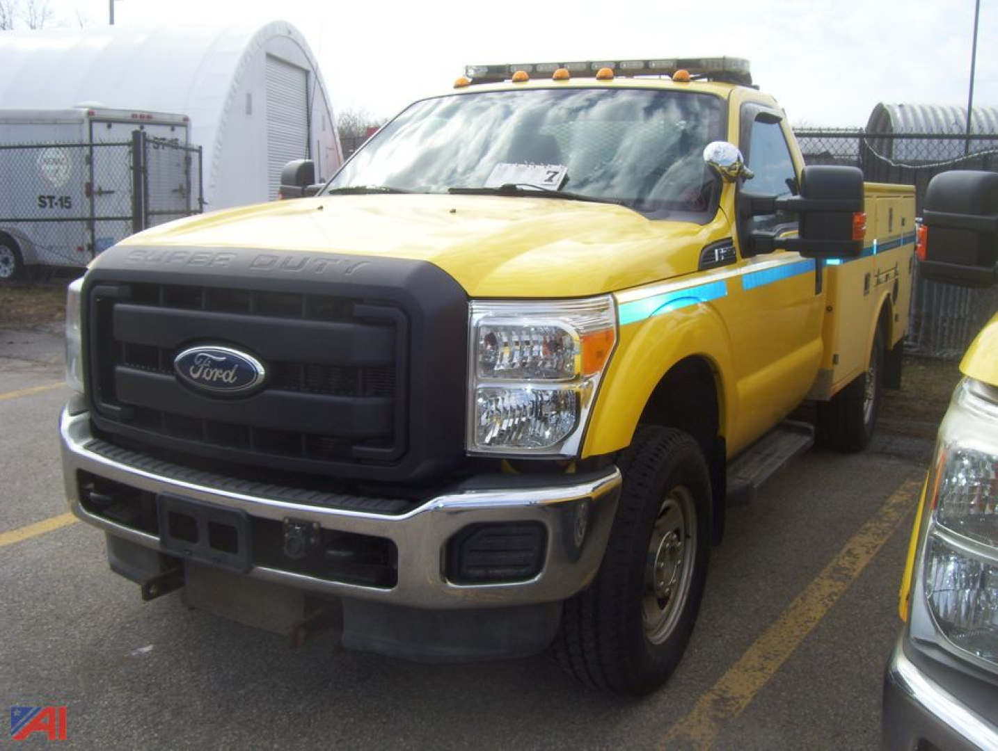 Ford F-350 utility truck with plow showing front grille and yellow body with blue stripe.
