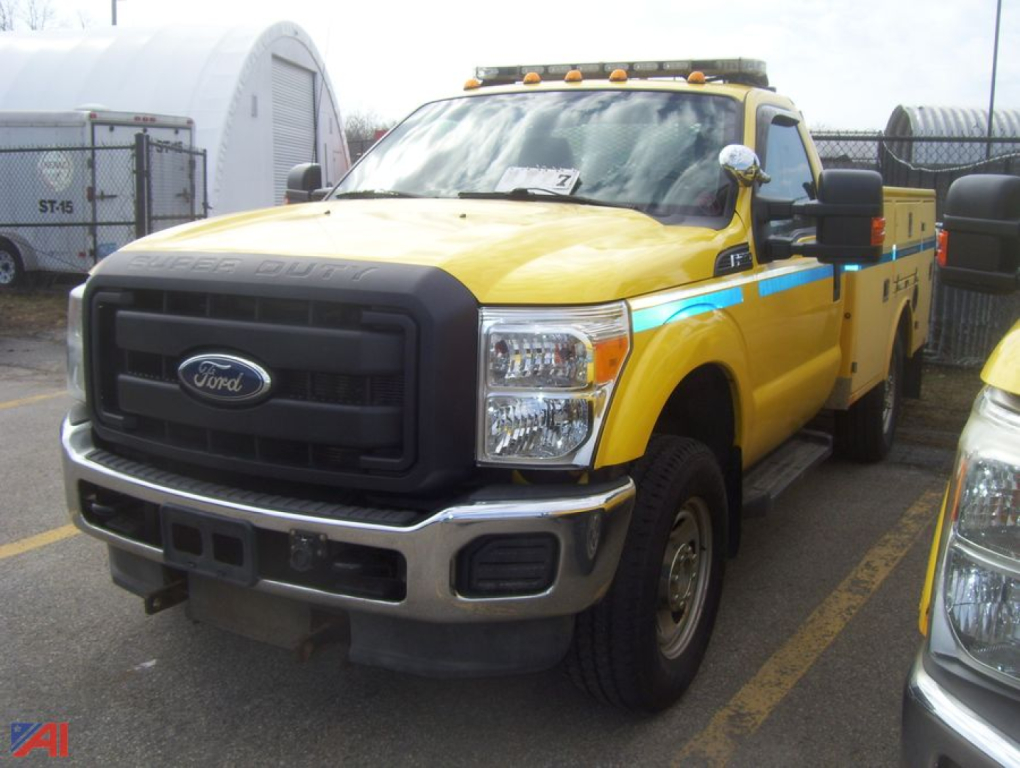 Ford F-350 utility truck with plow showing front grille and yellow body with blue stripe.