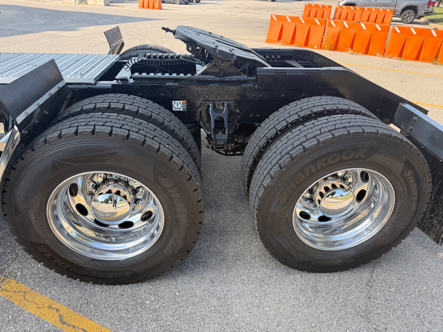 Peterbilt 389 chassis with tandem rear wheels and dual tires, chrome rims, visible suspension and leaf springs, no cab visible.