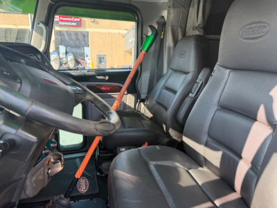 Peterbilt 389 cab interior with steering wheel, driver seat, and passenger seat visible; dashboard and windshield; manual gear area; general text not legible.