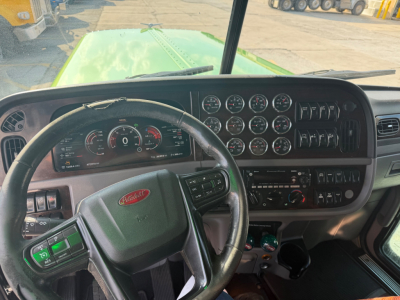 Peterbilt 389 cab interior dashboard and steering wheel with multiple gauges and controls visible.