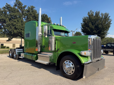 Peterbilt 389 conventional sleeper truck in green, front-right view showing chrome grille, large air intakes, dual exhaust stacks, and aluminum steps.