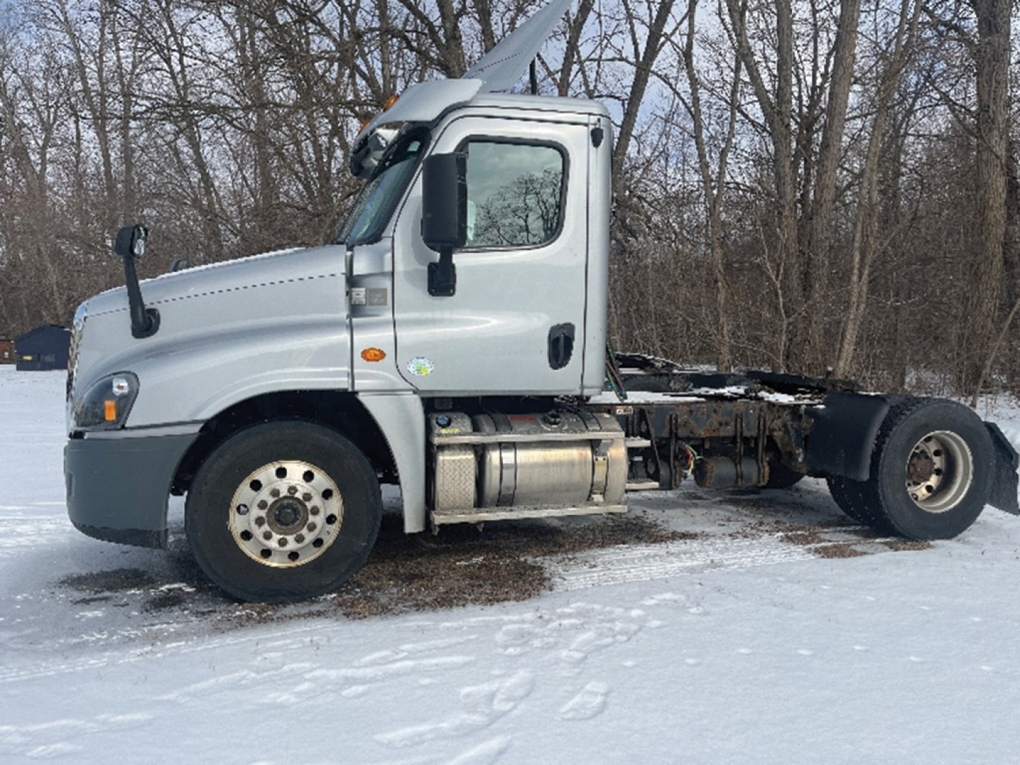 Side view of a 2018 Freightliner Cascadia125 conventional daycab truck chassis in snow, with cab, fuel tank, and rear undercarriage visible.