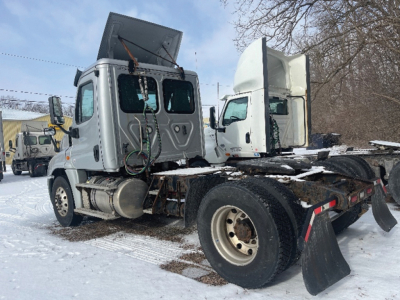 Truck chassis with cab and dump bed removed, rear wheels and fifth wheel visible; snow on ground. No legible text on components.