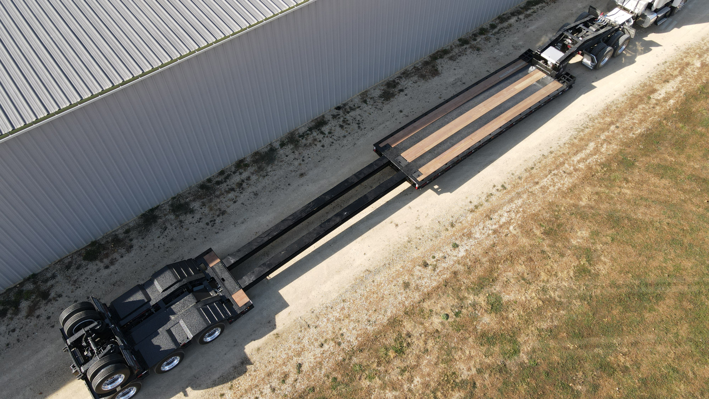 Trailer side view showing extendable lowboy deck with hydraulic detour extendable sections and cab over truck unit.