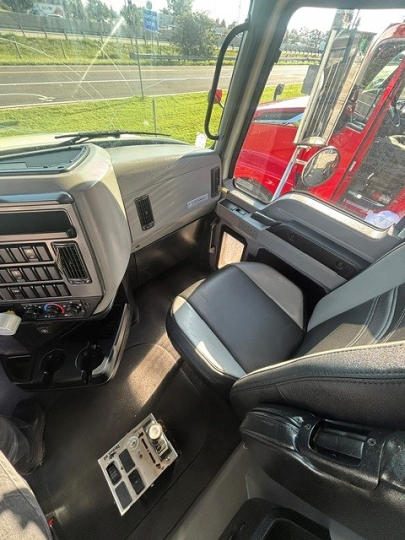 Cab interior of a 2022 Mack Granite dump truck showing front dashboard and passenger seat with steering column and gear selector area.