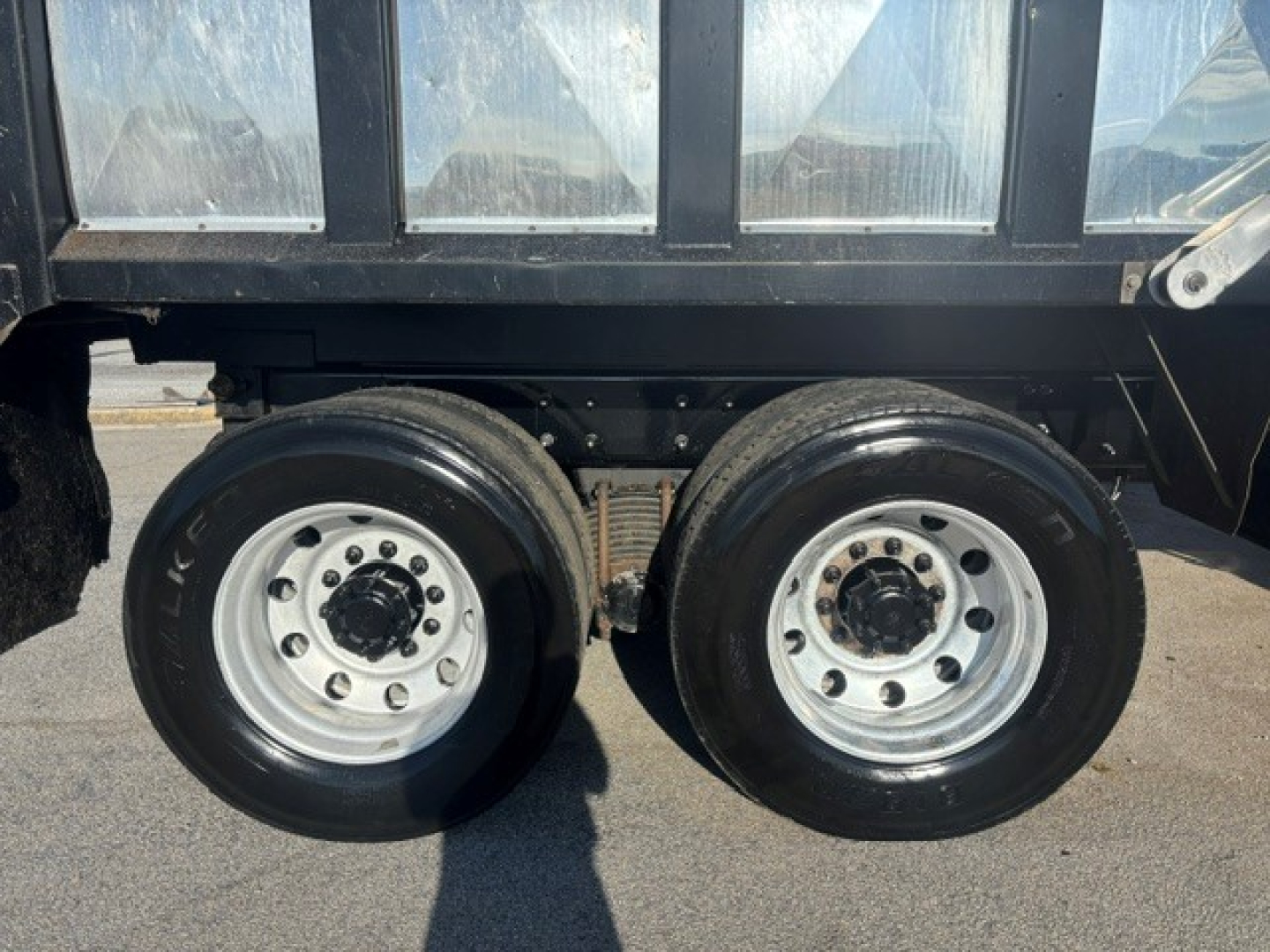 Dual rear wheel dump truck axle with black tires and polished silver rims under a Mack GRANITE dump body.