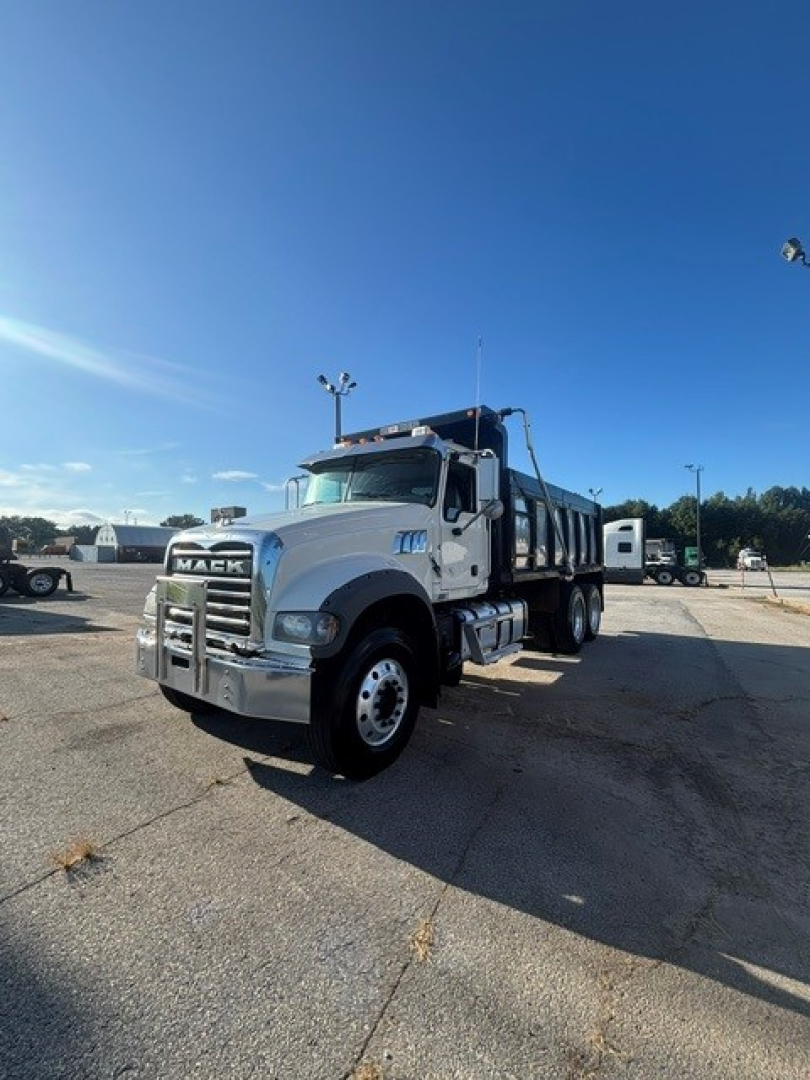 Truck: Mack GRANITE dump truck in a parking lot with front grille and headlights visible; side shows cab and hopper, text on front grille says MACK.
