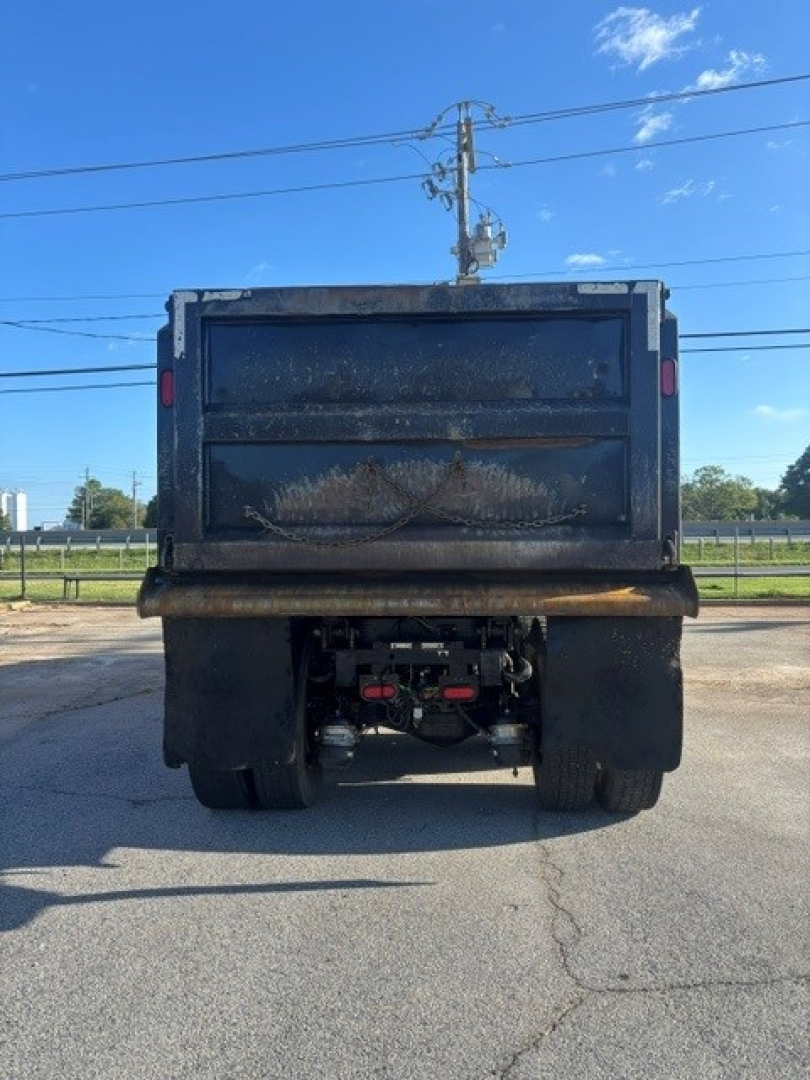 Dump truck rear showing tailgate and Dreary metal surface; Mack Granite dump bed with dual rear wheels and hydraulic components visible under tailgate.