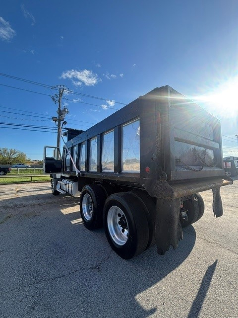 Dump truck rear side showing Mack GRANITE dump body and dual rear axles with black bed and reflective windows.