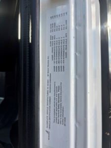 Label plate on Mack Granite truck showing various specification lines and VIN area, with printed small text.