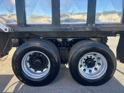 Dual rear wheels of a Mack Granite dump truck showing two silver rims and black tires beneath a metal frame.
