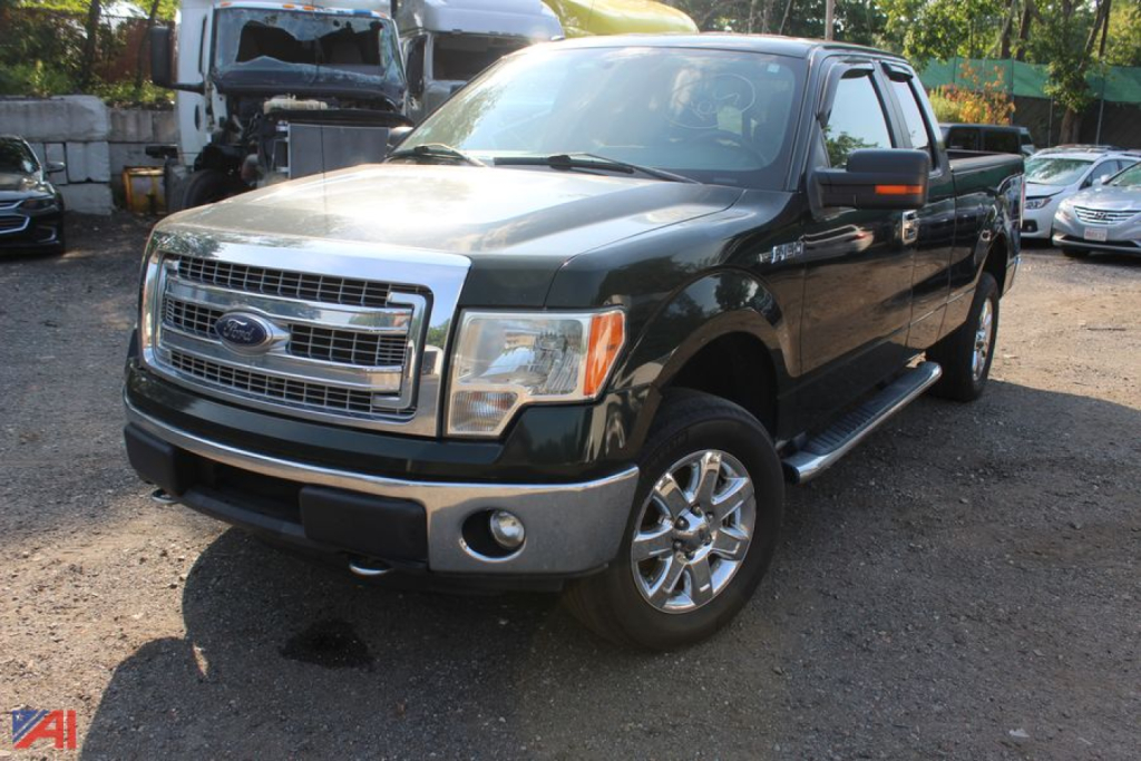 Ford F-150 pickup truck in a used lot, green body, chrome grille, four-door crew cab, running boards visible.