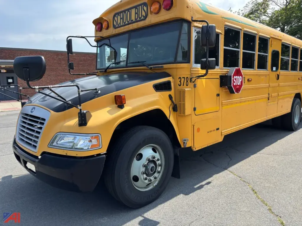 School bus showing front-left view with yellow body, black hood, stop sign, and numbering 378 on door. 'SCHOOL BUS' sign on roof, blue reflecting windows, blue sky background.