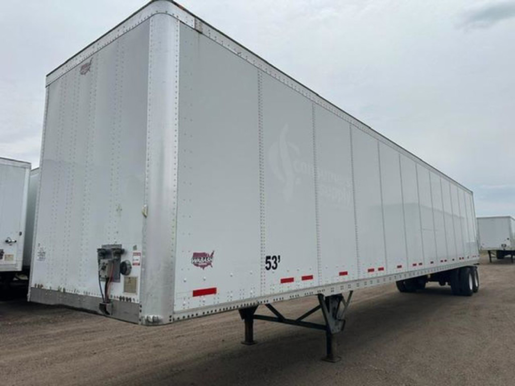 Trailer side view showing a 53' white aluminum van trailer with wheel drops and entry door, no visible branding.