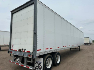 Trailer side view showing a white Wabash van semi-trailer with dual rear axles and red reflective markers.