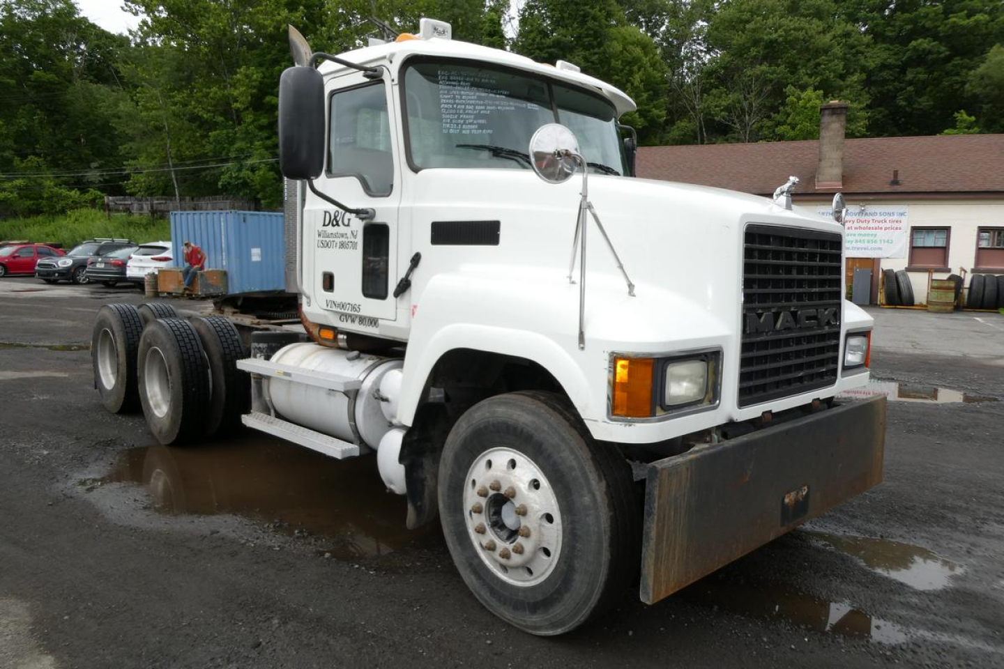 Truck cab and front chassis of a white 2006 Mack CHN613 daycab showing front grille, bumper, and dual rear axles with tires.