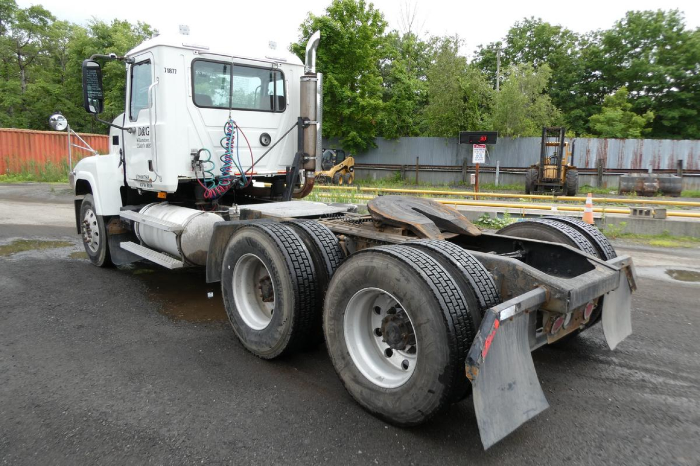 Mack CHN613 conventional daycab tractor visible from side, with dual rear axles and fifth wheel, white cab, chassis components and cables in view.