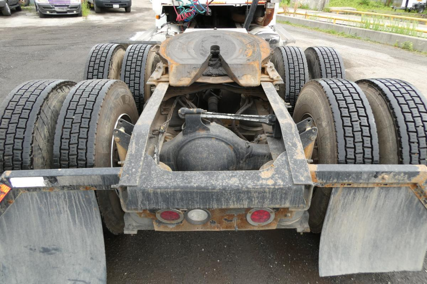 Rear view of a Mack CHN613 truck chassis showing dual rear axles, mud flaps, and hitch with rust-free rails; visible tires and frame components.