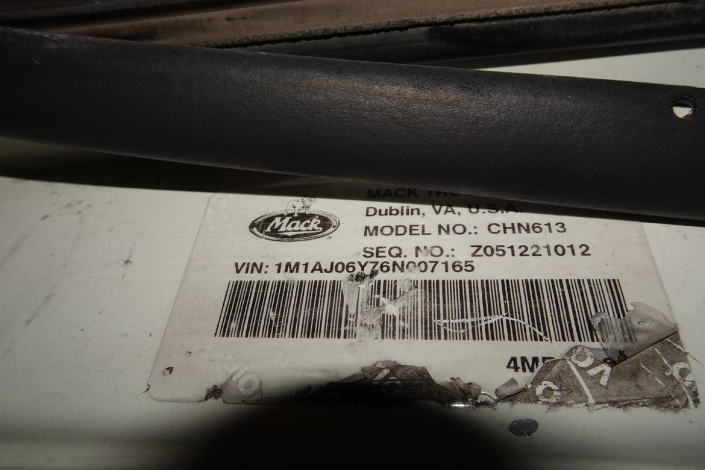 Mack CHN613 label with VIN 1M1AJ06Y76N007165 and barcode on white tag, under a black bar.