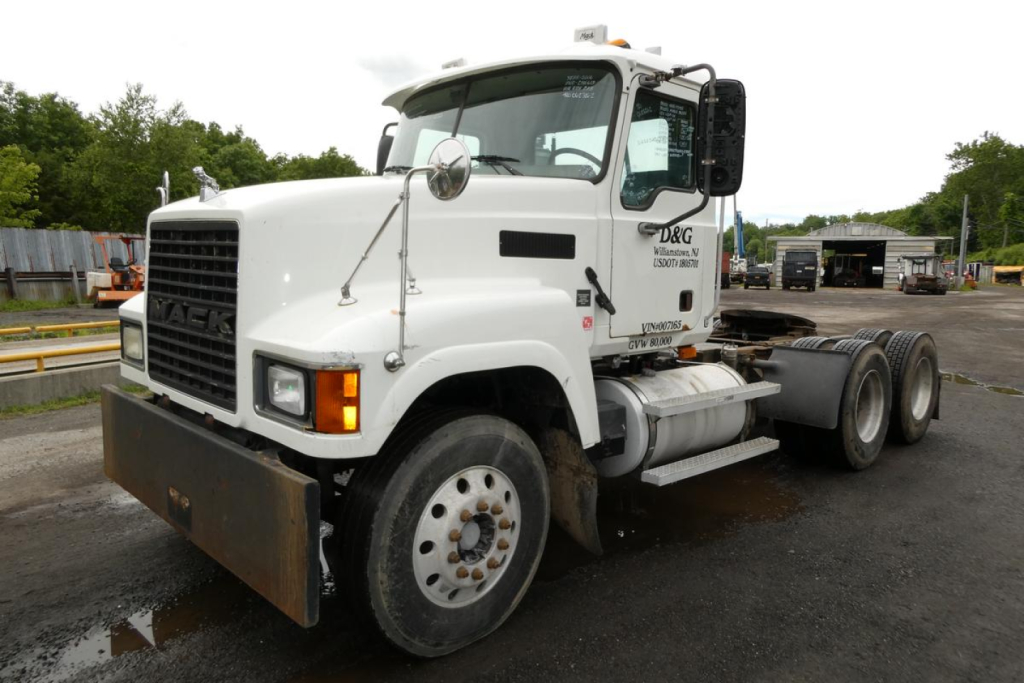 Mack CHN613 conventional daycab truck in white viewing left front three-quarter with front bumper guard and dual rear axles.