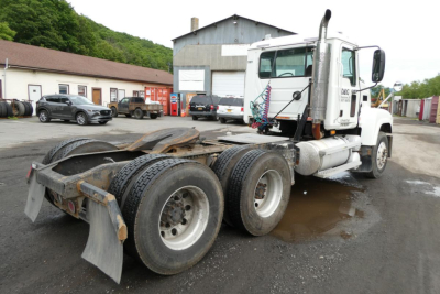 Mack CHN613 conventional daycab tractor rear chassis and dual rear axles with 6x4 configuration showing tires and mud flaps.
