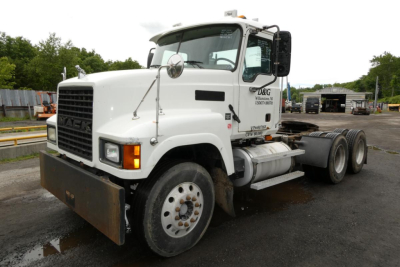 Mack CHN613 conventional daycab truck in white viewing left front three-quarter with front bumper guard and dual rear axles.