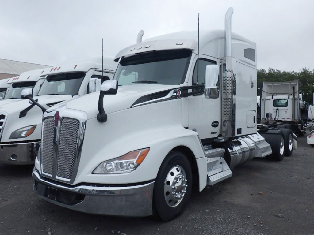 Kenworth T680 Next Gen sleeper tractor in white, side view showing front grille, hood, chrome bumper, large fuel tanks, and chrome exhaust stacks.