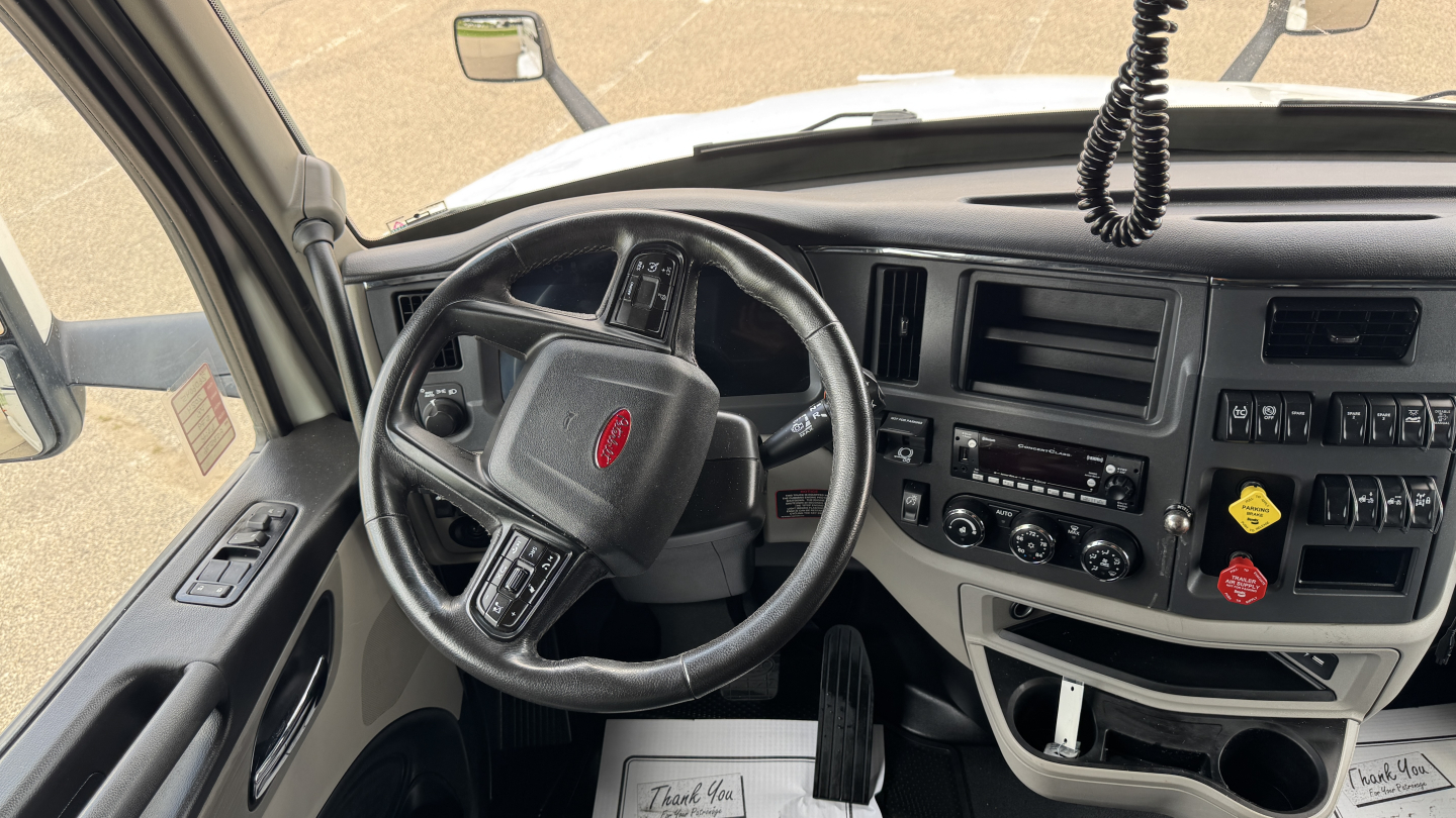 Peterbilt trucks cab interior showing steering wheel and dashboard with controls and vents.