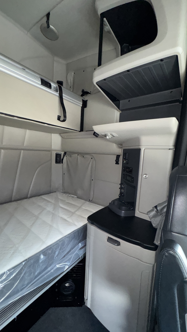 Truck cab interior showing sleeper berth with storage compartments and cabinetry in a Peterbilt 579.