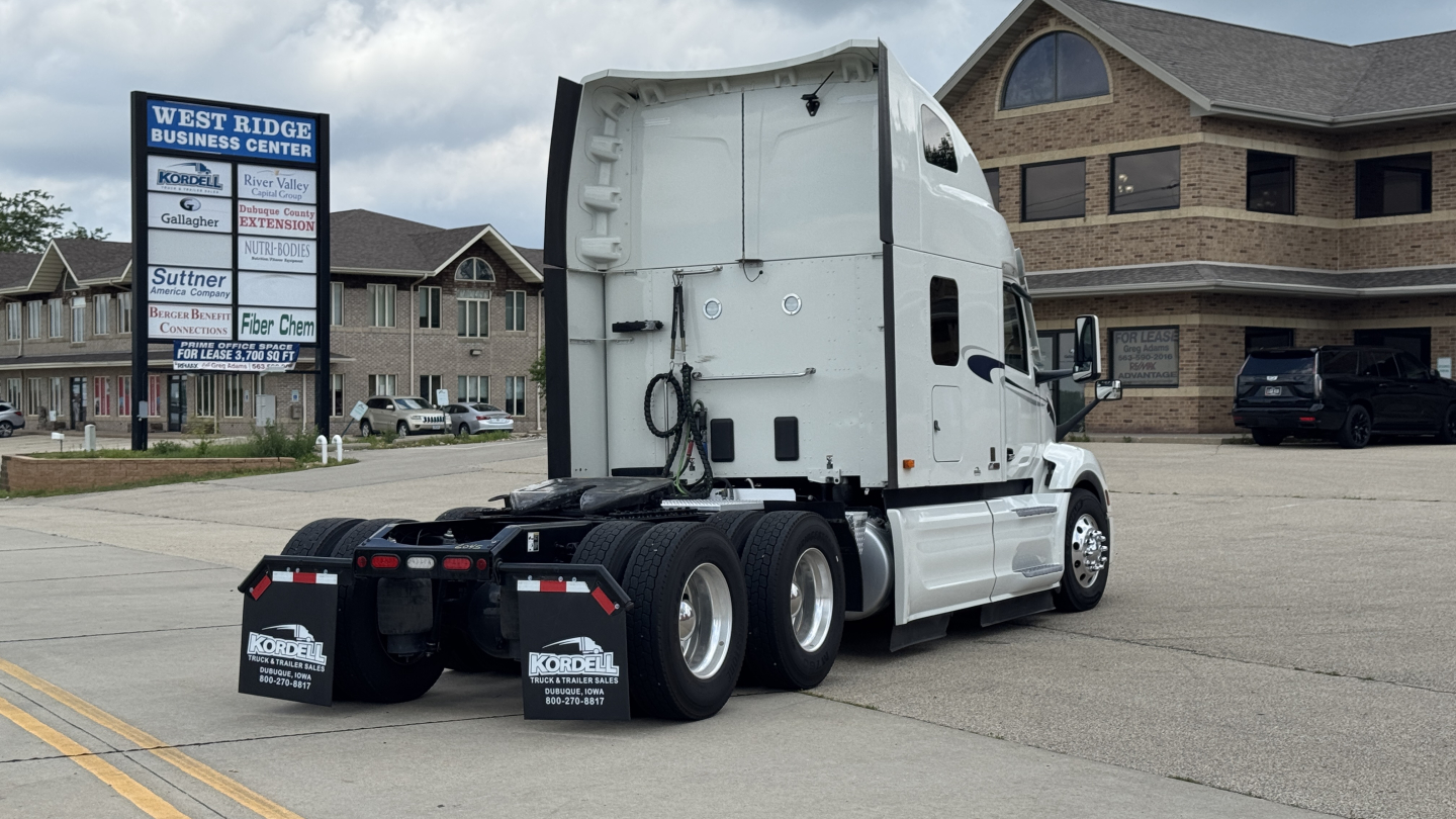 Truck rear and side view of a white 2024 Peterbilt 579 conventional sleeper tractor showing dual rear axles and hitch area