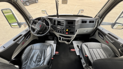 Peterbilt 579 cab interior showing steering wheel, dashboard, and two front seats from driver and passenger doors open.
