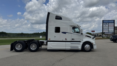 Peterbilt 579 conventional sleeper truck side profile showing white cab and dual rear axles with chrome wheels
