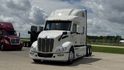 Peterbilt 579 tractor trailer cab in white, sleeper, front view showing chrome grille and headlights.