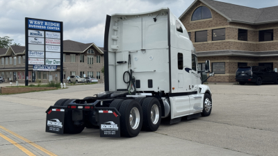 Truck rear and side view of a white 2024 Peterbilt 579 conventional sleeper tractor showing dual rear axles and hitch area