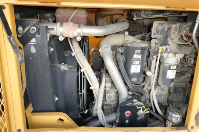Engine bay of a CAT diesel generator or industrial engine with hoses, radiator, filters, and CAT branding visible.
