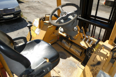 Forklift operator seat and steering wheel area of a yellow Master Craft C08-17166 forklift showing dashboard, pedals, and control levers.