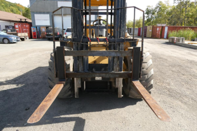 Forklift forks extending forward in a truck lifting machine, front view showing wear on tines and carriage.
