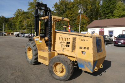 Industrial forklift in yard with tires and lifting forks, side text reads 'MASTER CRAFT' and 'MC-8041' on yellow frame.
