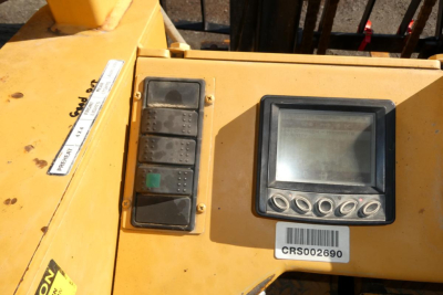 Machine control panel and display screen on yellow lifting equipment with several push buttons and a barcode sticker CRS002690.