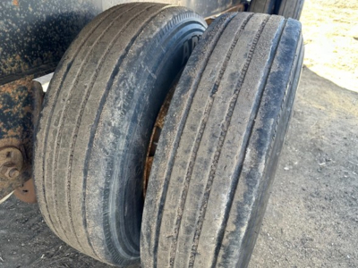 Dual trailer wheels with flatbed equipment showing worn tires and side view