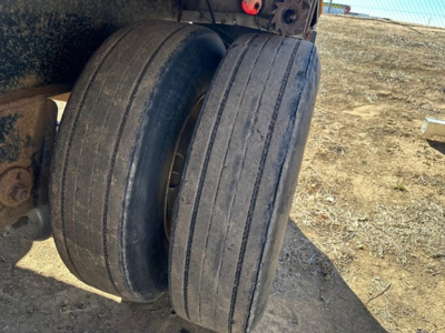 Two large trailer tires mounted on a utility spread air combo flatbed chassis. Visible are the dual axles and tire treads; no legible labels or brands clearly visible on the tires in this image.